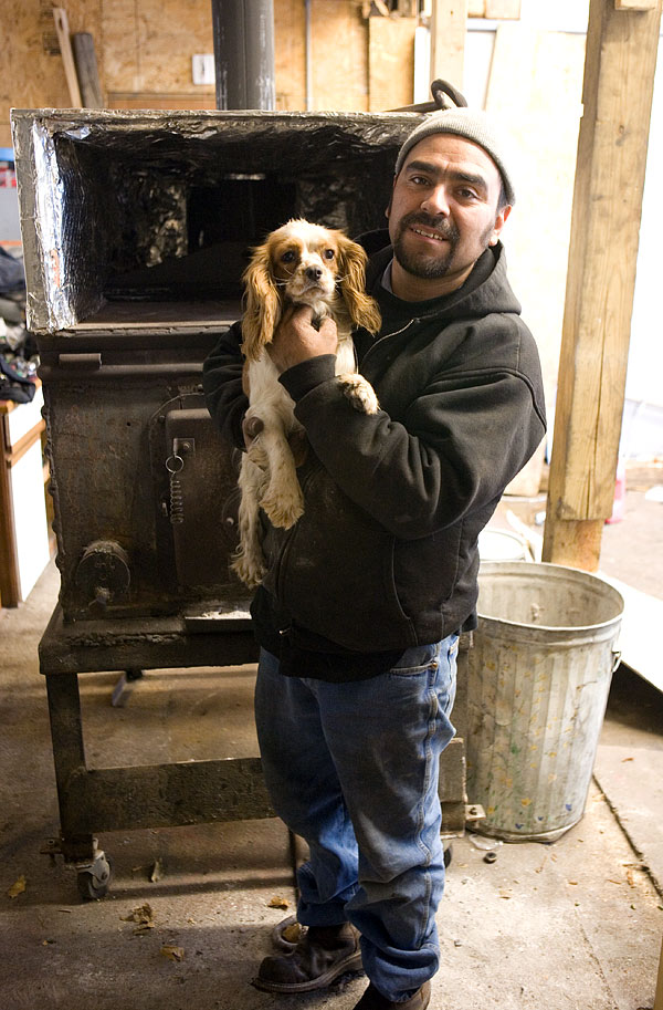 Agustin Loran, owner of Loran's Auto Repair, in front of his woodburning furnace, Logansport